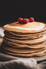Delicious stack of pancakes with berries on a dark background.