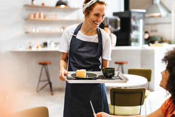 Female barista serving coffee and cake on a tray