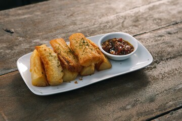 A plate of Indonesian pisang goreng tepung or fried banana with chilli sauce snack in white plate