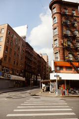 vintage building with fire escape stairs near pedestrian crossing on street corner in new york city