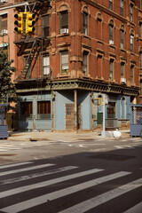 Obraz premium vintage building with fire escape stairs near pedestrian crossing in new york city, urban scene