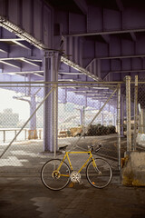yellow bicycle near metallic net fence over bridge in new york city, contemporary metropolis scene