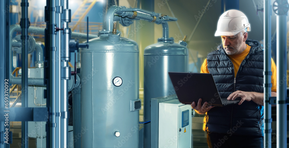 Poster man engineer in boiler room. industrialist with laptop. engineer controls heating equipment. man in 