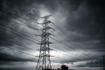 A power tower silhouetted against a dark and cloudy sky. 