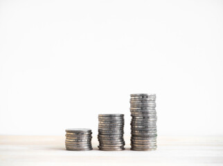 Investment, savings, growth financial business, Increase earning money, income and sales profit concept. Three piles of silver coin stack arranged as a graph step on wood desk and white background.