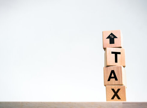 Taxation, tax rates ,increase and decrease of taxes trend concepts. Percentage in up arrow sign and text "TAX" on wooden cube blocks stack on wood table isolated on white background with copy space.