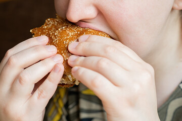 Woman bites sandwich. Girl eating burger close-up. Lady with appetite bites hamburger. Female eats...