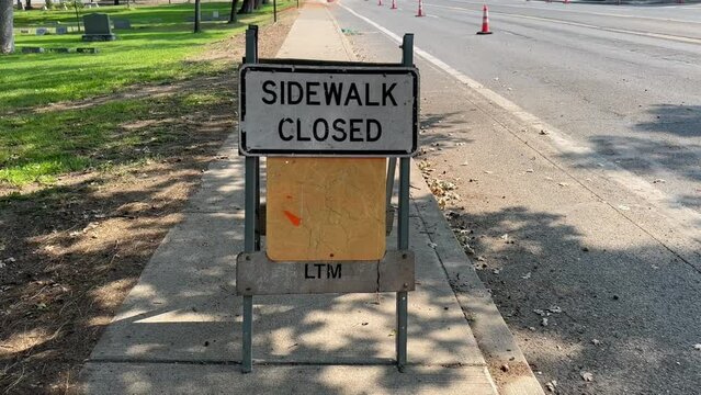 Sidewalk closed sign on the side of the road in the shade.
