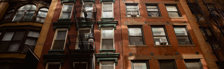 Obraz premium low angle view of vintage red brick house with fire escape stairs in new york city, banner