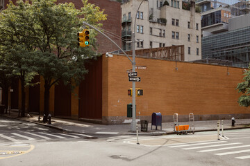 brick fence near road pole with traffic light of crossroad with pedestrian crossing in new york city