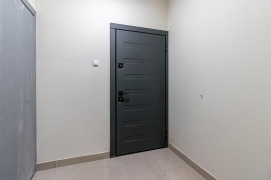 Dark entrance door to the apartment, against the background of a white wall
