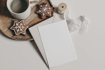 Christmas still life. Blank greeting card, invitation mockup. Star shaped gingerbread cookies, cup of coffee on wooden tray. Neutral white table background. Winter breakfast festive flatlay, top view.