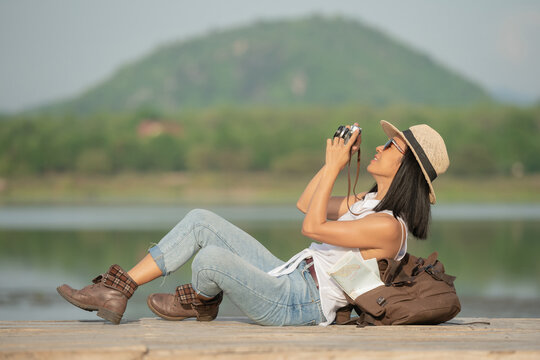 Hipster woman with backpack taking photo of amazing landscape sunset on vintage camera on peak mountain. Joyful asian woman travel vacation. Tourist traveler on background sunlight in trip in nature