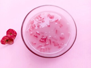 Candil porridge, a traditional snack made from starch and then eaten with coconut milk. chewy, sweet and savory. pink snacks. Bubur candil on pink background. Close up