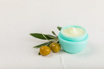 Obraz na płótnie Canvas Jar of natural olive cream with olive oil extract on a texture background. Cosmetic tube. Moisturizing cosmetic cream for skin. Body care. Beauty concept. Copy space. Flat lay. Hand cream.