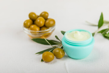 Jar of natural olive cream with olive oil extract on a texture background. Cosmetic tube. Moisturizing cosmetic cream for skin. Body care. Beauty concept. Copy space. Flat lay. Hand cream.