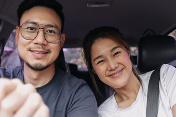 Asian Thai couple smiling happy time while driving a car on road, enjoy vacation holiday.