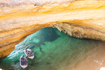 Benagil cave in Algarve Top down view. Tourists in tours boats enjoying the cave view. Blurred...