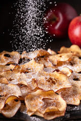 in the foreground, slices of homemade dried apple flavored with a cascade of icing sugar