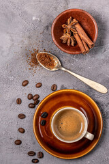 espresso coffee in cup, flavored with cinnamon and star anise, top view on gray textured background