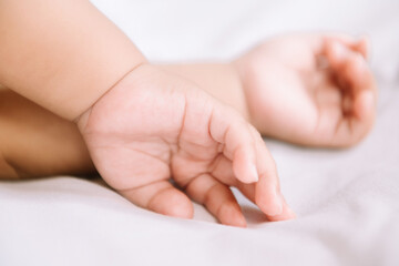 Hands of the woman and a child's hand on the white bed
