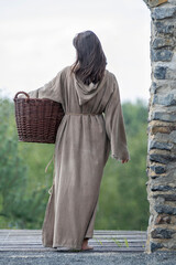 Medieval maid with long hair and basket as rear view