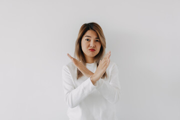 Asian Thai woman grumpy face, showing stop, crossed arms sign gesture, prohibit action, giving negative feedback, rejecting no, isolated on white background in winter.