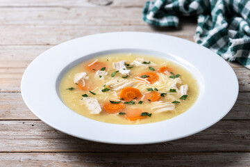 Chicken soup with vegetables on wooden table