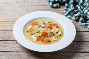 Chicken soup with vegetables on wooden table