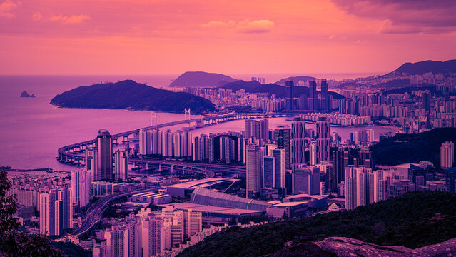 Busan City skyline at sunset over Haeundae Beach Harbor with skyscraper buildings, office towers, Gwangalli Bridge, Oryukdo Islands, and Jangsan Mountain in South Korea, monotone at foggy twilight