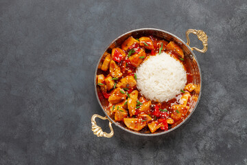 Chicken fillet in sweet and sour sauce with paprika. Rice side dish.