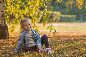 Portrait of a little girl 4 years old outdoors. A happy child in the autumn park. Happy childhood and fatherhood.