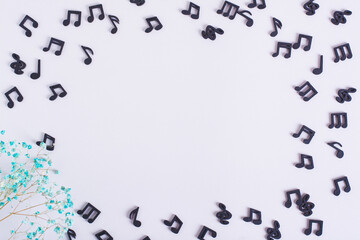 Musical concept frame made of black notes and dried flowers on a light background