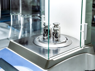 Close-up of three weights used to calibrate an analytical balance.