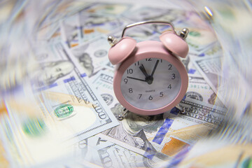pink quartz alarm clock isolated on US 100 dollar banknotes