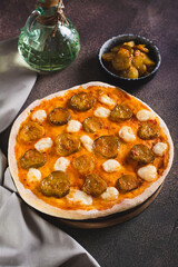 Spicy pizza with cheese and pickles on a wooden board on the table vertical view
