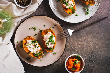 Baked sweet potato stuffed with ricotta, tomatoes and herbs on a plate top view
