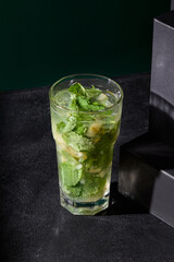 Freshly crafted lemonade with pear and mint highlights, casting bold shadows against its dramatic black backdrop. A symphony of flavors and aesthetics
