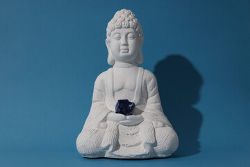 Buddha statue and natural stone on blue background