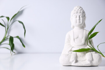 Buddha statue and leaves on white background, space for text