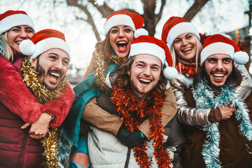 Happy friends wearing santa claus hat celebrating Christmas eve together - Young people having fun...