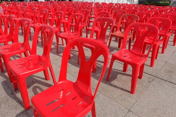 Red chairs for attendees of meetings, seminars, and recreational activities. Arrange them in rows in an outdoor location.