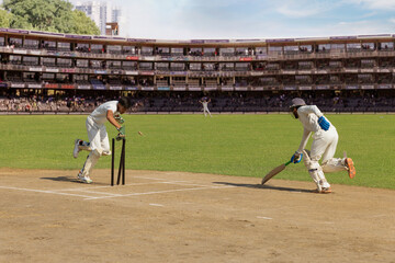 Batsman taking a run as the wicket keeper tries to run him out during a cricket match