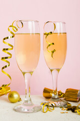 Champagne glasses and christmas decor on colored holiday background. Flat lay New Year decorations
