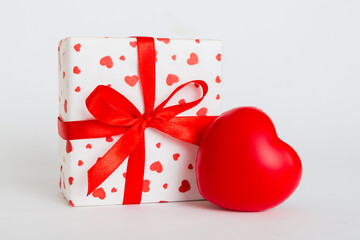 gift box with red bow and red heart on colored background. Perspective view. Flat lay