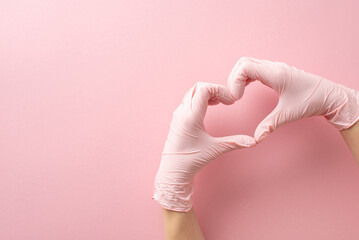 Embracing my medical journey. First person top view of female medic's hands, clad in surgical gloves, craft a heart gesture on soft pink. A canvas for your message