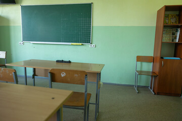 empty classroom without students in school chairs and desks, board in Ukraine.