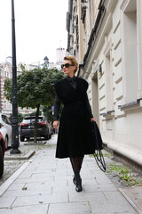 Dojrzała, elegancka kobieta na miejskim spacerze.
Kobieta w czerni. 