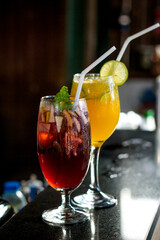 Iced strawberry soda and lemon, a refreshing drink, placed on a classic wooden table decorated with lemon petals and various fruits.