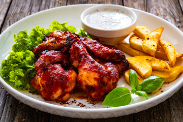 Buffalo wings with ranch dressing and French fries on wooden table
